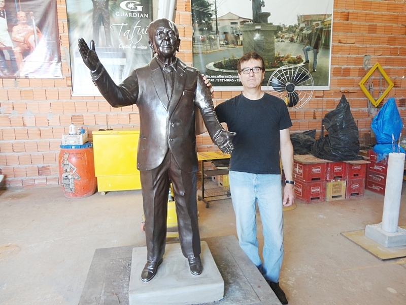 Cláudio ao lado da escultura do saudoso professor Paulo Ribeiro.